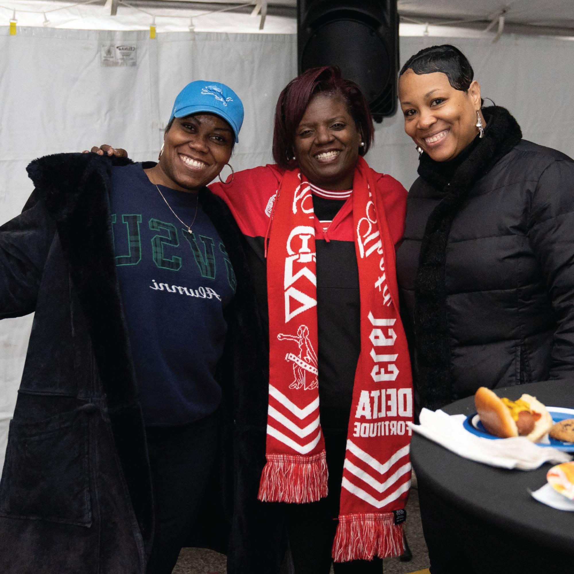 A Photo of three alumni celebrating homecoming in the alumni tent